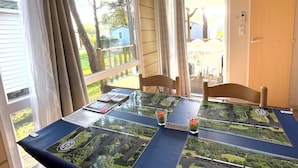 A table with a 'Bienvenue' sign, a glass with a flower, and a view of the outdoors through large windows.