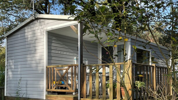A small wooden cabin with a porch, surrounded by trees.