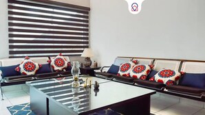 A modern living room with a sofa set, patterned cushions, a glass coffee table, and a lamp.