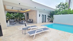 A modern outdoor pool area with lounge chairs and a dining setup.