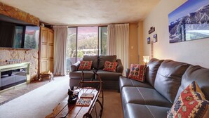 A living room with a brown leather sofa, a wooden coffee table, and a stone fireplace. - Pet Friendly, Spacious, Mountain Views SB102 (Copper Mountain)