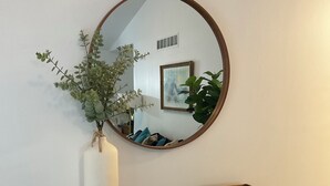 A wooden console table with a mirror above it, a vase with green foliage, and a tray with books. - Charming 3-bedroom cottage with AC in marvelous Saugatuck close to trails (Saugatuck)