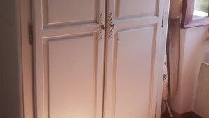 Une pièce avec une grande armoire blanche, un radiateur et une fenêtre avec des rideaux.