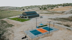 Ein modernes Gebäude mit einer großen Garage und einem Tennisplatz.
