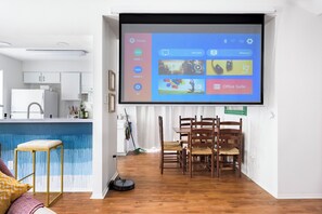 A modern living room with a large screen displaying a home entertainment system interface.
