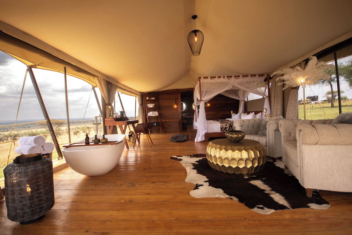A spacious room with a large wooden floor, a white bathtub, a sofa, and a cowhide rug.