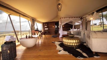 A spacious room with a large wooden floor, a white bathtub, a sofa, and a cowhide rug.