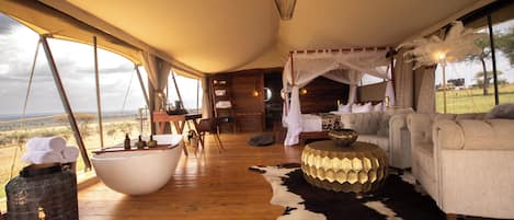 A spacious room with a large wooden floor, a white bathtub, a sofa, and a cowhide rug.