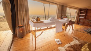 A tented room with a wooden floor, a table with towels and toiletries, and a view of the landscape. - Serengeti Luxury Retreat (Serengeti)