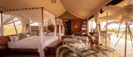 A tented accommodation with a bed, a sofa, and a dining area.