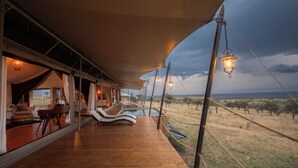 A wooden deck with a pool, outdoor seating, and a view of the savannah. - Serengeti Luxury Retreat (Serengeti)