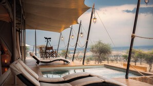 A pool area with lounge chairs, a table, and a telescope. - Serengeti Luxury Retreat (Serengeti)