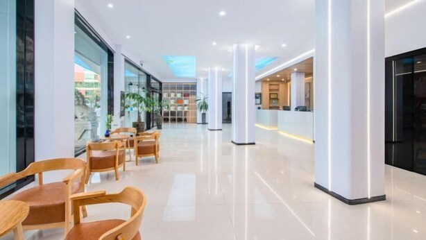 A modern hotel lobby with a reception desk, seating area, and large windows. - Longgang Hongmao Film Hotel (Longgang)