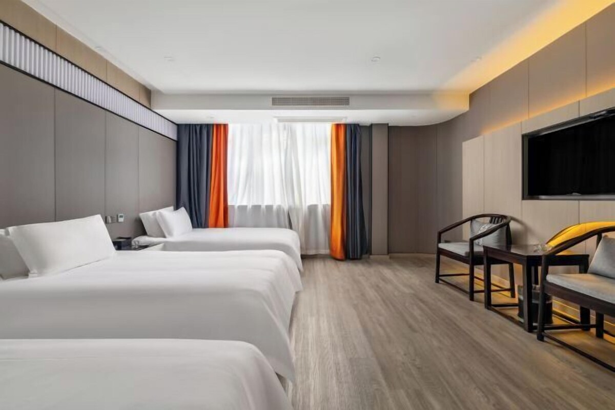 Une chambre d’hôtel avec deux lits, une télévision, un bureau et une chaise.
