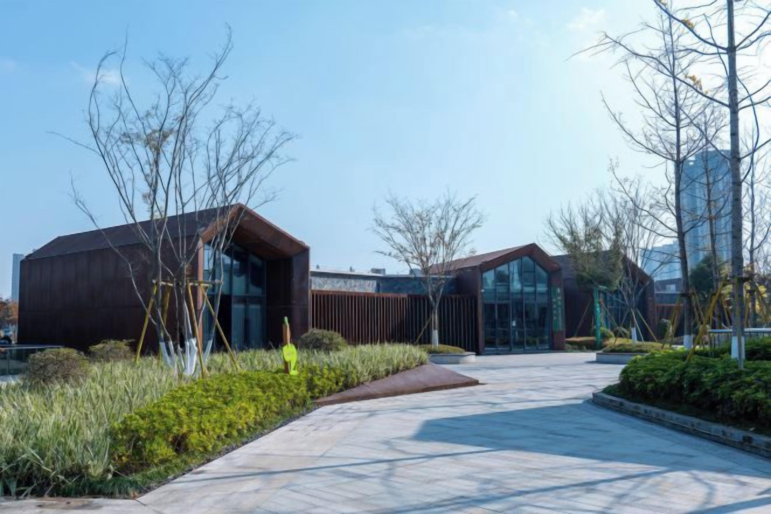 A modern building with a glass facade, surrounded by a landscaped area with pathways and greenery.