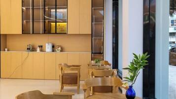 A modern interior with wooden furniture, a blue vase with a plant, and a kitchen area with cabinets and appliances.