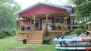 A red house with a wooden deck, a staircase, and a porch with potted plants. - Cranberry Moon Inn B&B (Bala)