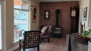 A cozy living room with a fireplace, wooden flooring, and a view of the outside. - Cranberry Moon Inn B&B (Bala)