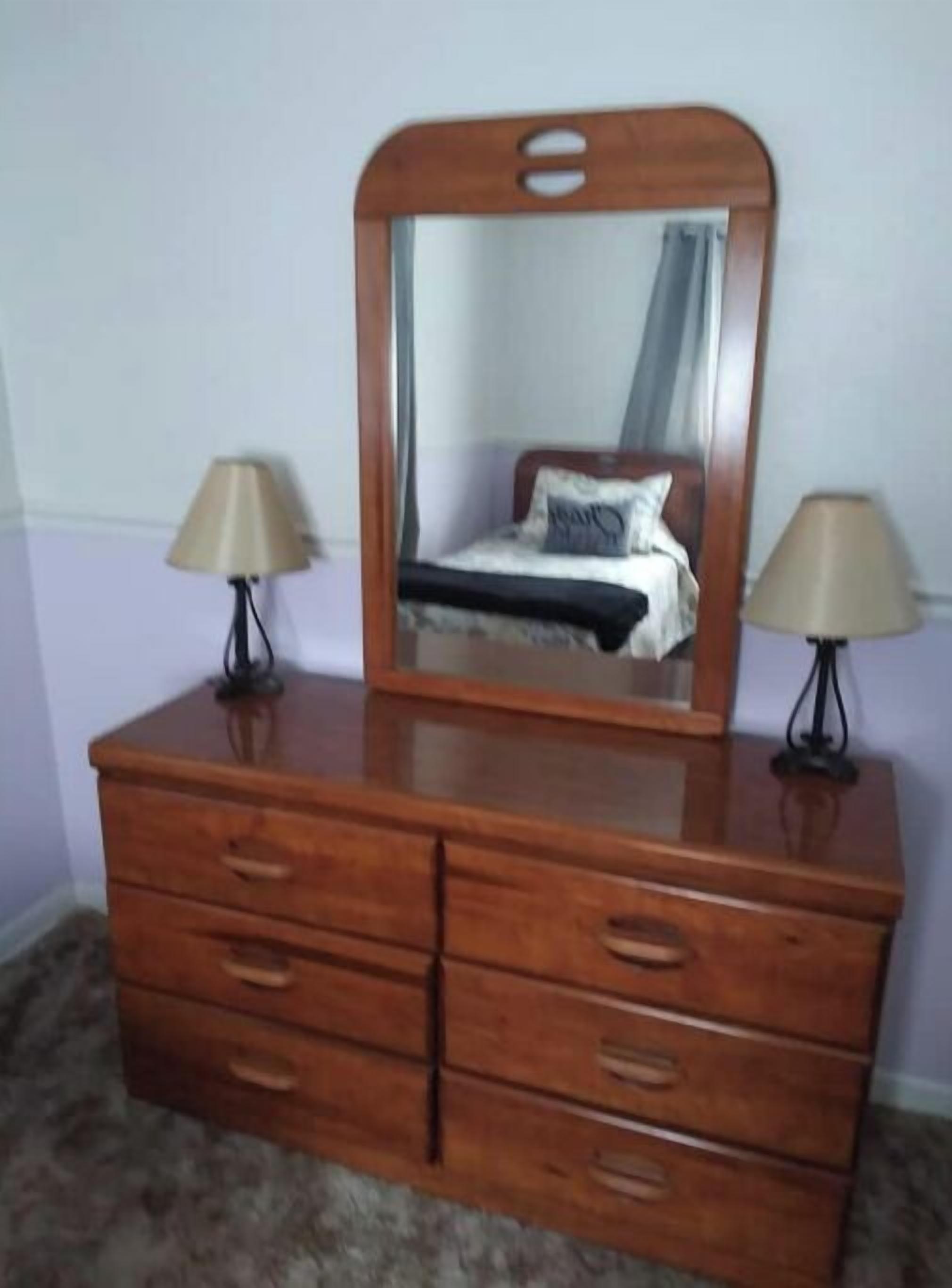 A wooden dresser with multiple drawers and a mirror above it.