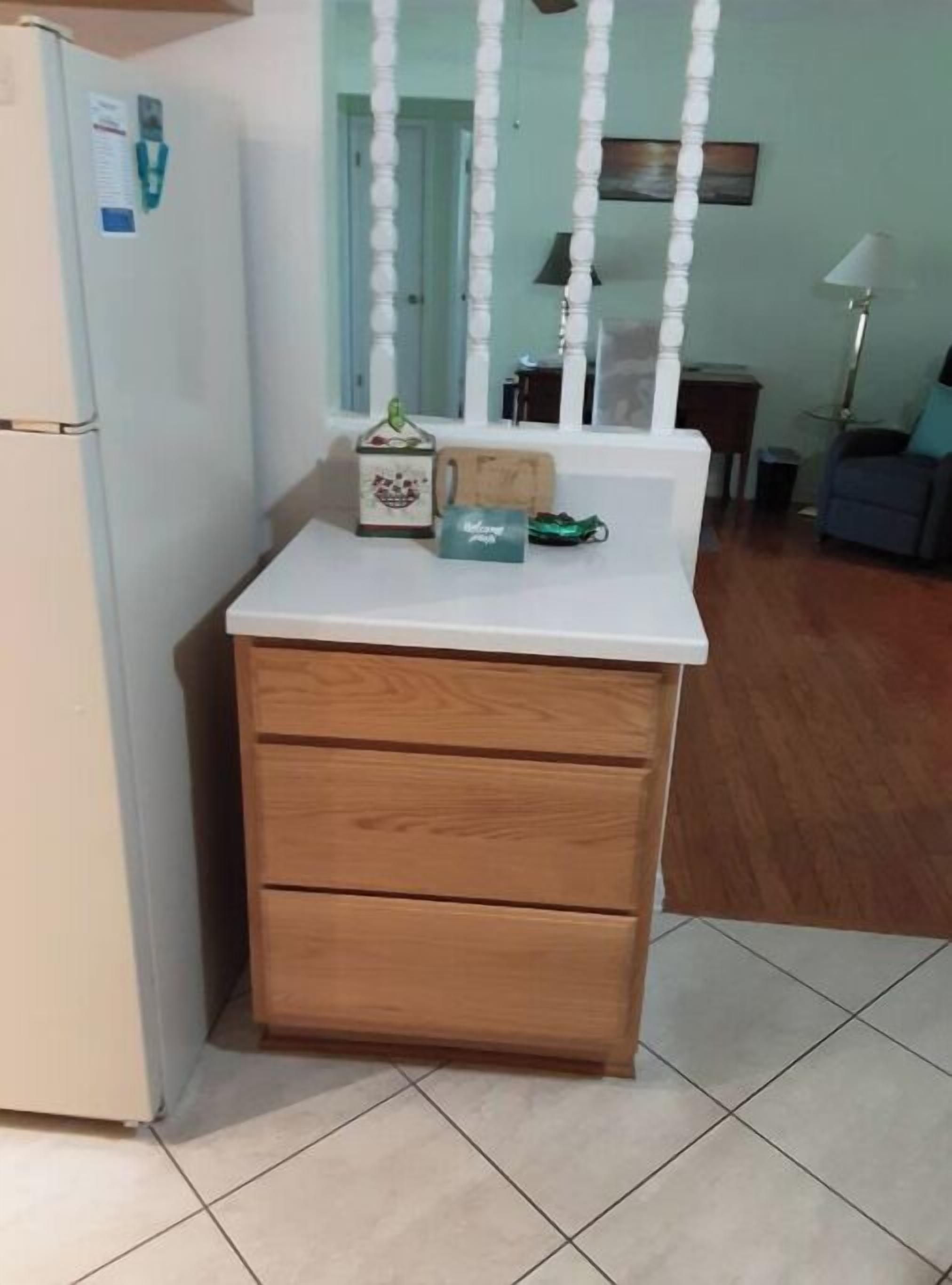 A kitchen with a white refrigerator, wooden cabinets, and a tiled floor.