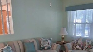 A living room with a plaid sofa set, a round coffee table, and a lamp. - Entire 2 bedroom home w/1 car garage in Inverness (Inverness)