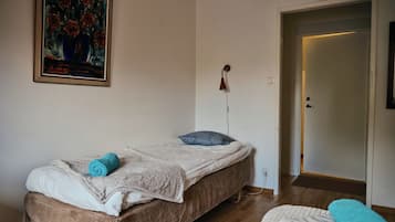 Una habitación con una cama, un cuadro, un reloj y una puerta.