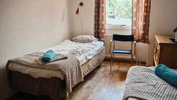 A small, tidy bedroom with a single bed, a chair, and a desk.