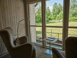 A room with a large window, a chair, a table, and a lamp. - Herrestad Bed & Guestroom (Varnamo)