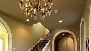 A grand staircase with a chandelier, leading to a door with a blue stripe.