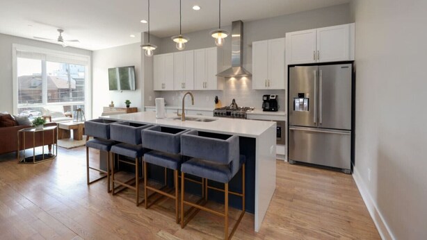 A modern kitchen with a central island, stainless steel appliances, and pendant lighting. - Spacious West End | Rooftop Skyline Retreat (Nashville)