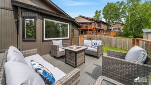 Un patio con mobiliario de mimbre, una chimenea y vistas a casas vecinas.