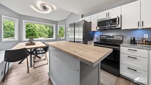 Una cocina moderna con armarios blancos, electrodomésticos de acero inoxidable y una isla de madera.