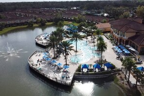Een resort met een centraal gelegen zwembad, palmbomen en een steiger.