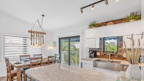 A modern kitchen with a large island, white cabinetry, and a view to the outdoors. - P61 - 2 Bed, 2 Bath with coastal chic vibe and private pool. (Marathon)