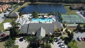 An aerial view of a resort with a swimming pool, tennis courts, and a large lake. - Paradise Palms 4BR | Private Pool & Themed Rooms (kissimmee)