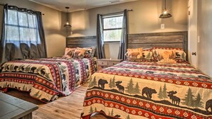 Une chambre dotée de deux lits, chacun agrémenté de draps à motifs représentant des imprimés d’animaux, d’une tête de lit en bois et d’un ventilateur de plafond.