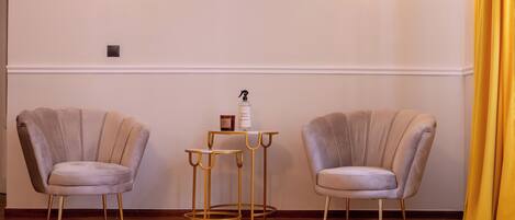 A room with two upholstered chairs, a small table, and a lamp.