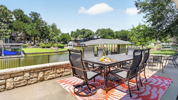 An outdoor patio with a table and chairs, a view of a water body, and a gazebo in the background. - The Spot at Lake Granbury (Granbury)