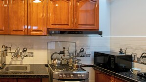 Een keuken met houten kastjes, een rvs fornuis, een magnetron en een spoelbak.
