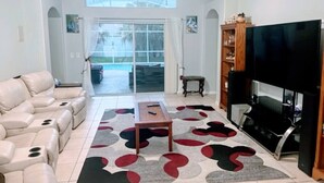 Ein Wohnzimmer mit einer Eckcouch, einem Flachbildfernseher und einem gemusterten Teppich.