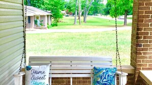 Eine Veranda mit einer Schaukel, einer Bank und einem Schild mit der Aufschrift 'Home Sweet Home'.