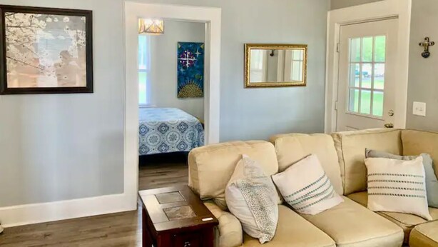 Ein Wohnzimmer mit einem beigen Sofa, einem kleinen Holztisch und einem Bild an der Wand.