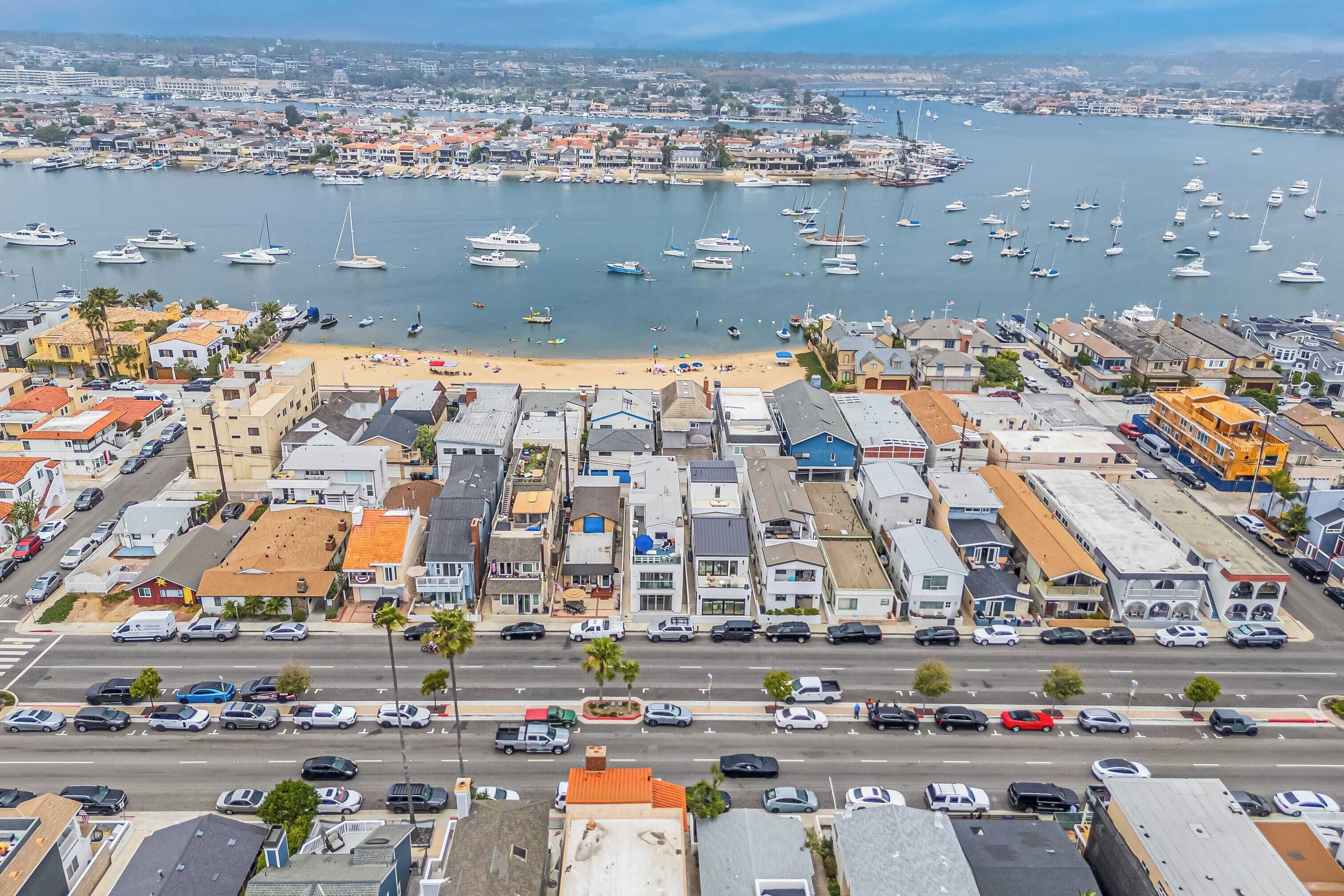 A coastal town with a marina, sandy beach, and a variety of buildings including residential and commercial properties.