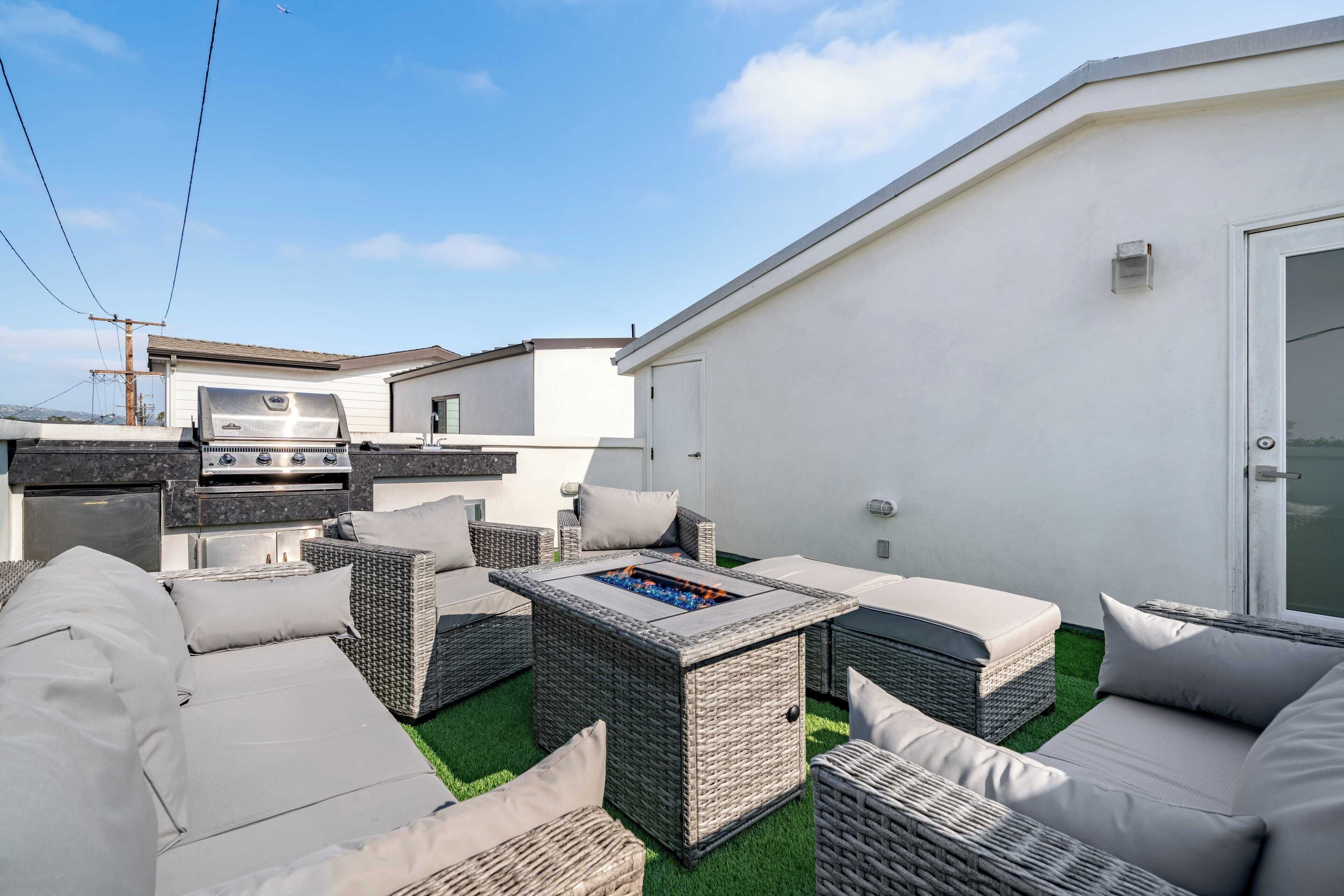 Eine Terrasse mit Gartenmöbeln, einem Grill und einer Feuerstelle.