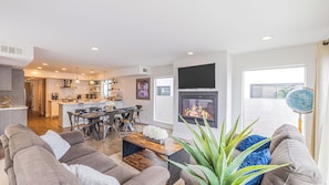A modern living room with a fireplace, a dining area, and a kitchen. - Private Rooftop + Steps to the Beach Chic Design Seaside Style by Avantstay (Newport Beach)