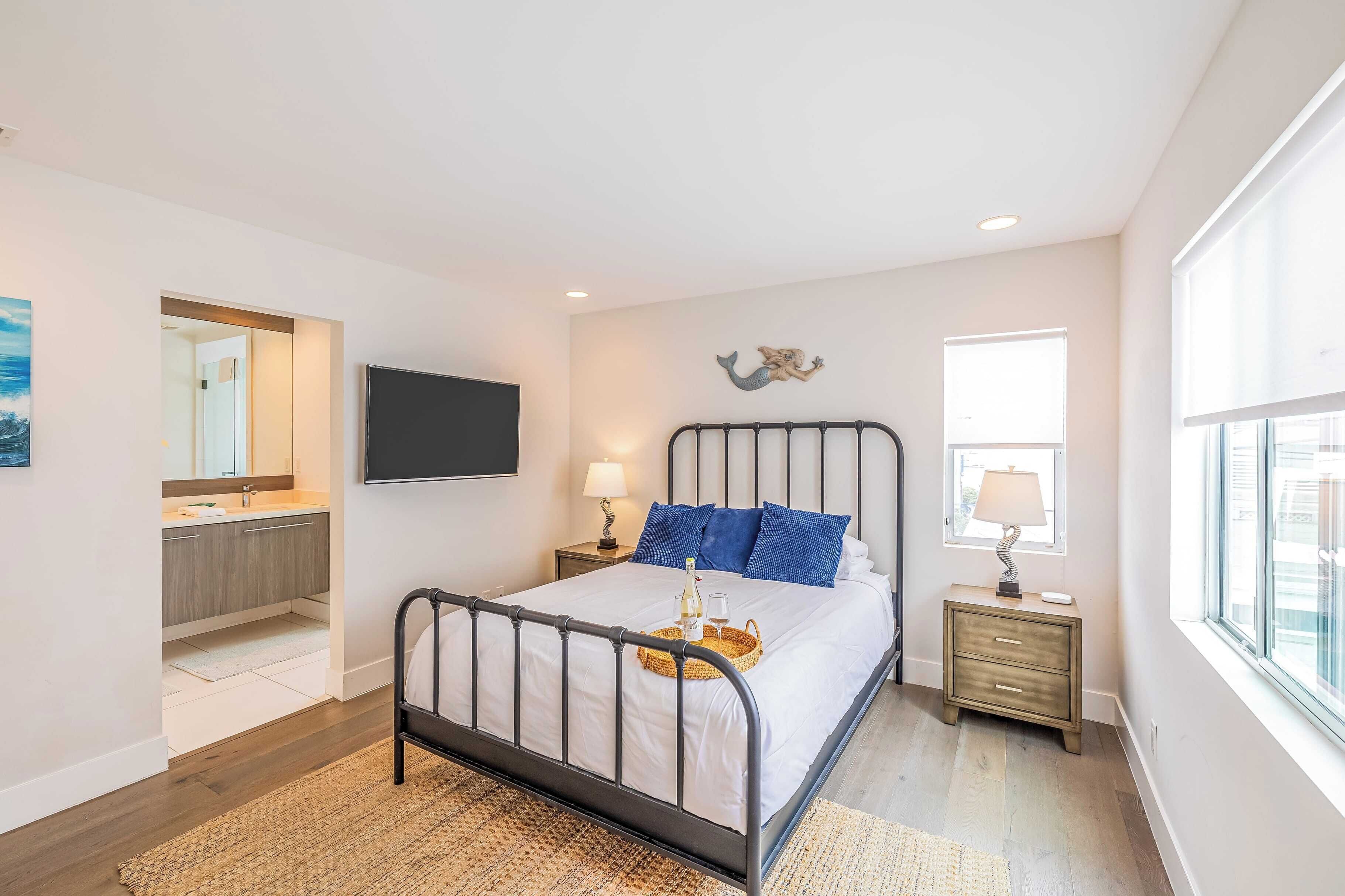 A modern bedroom with a bed, bedside tables, a TV, and a window.