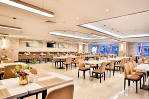 Un'ampia sala da pranzo con diversi tavoli e sedie, un design moderno e pulito e un'ampia finestra con vista sulla città.