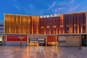Un hotel con facciata moderna, caratterizzata da listelli verticali in legno e insegne illuminate.