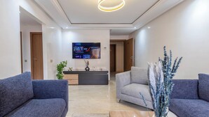 A modern living room with two sofas, a TV, and a decorative vase. - Stylish apartment with swimming pool, sauna and hammam in central Marrakech   (Marrakech)