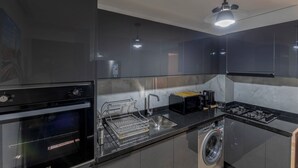 A modern kitchen with a built-in oven, a washing machine, and a sink. - Stylish apartment with swimming pool, sauna and hammam in central Marrakech   (Marrakech)